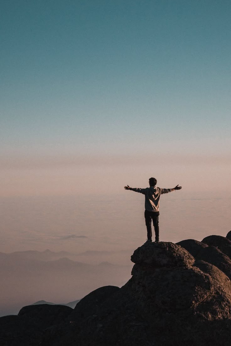 Person celebrating achievement with arms outstretched at sunset